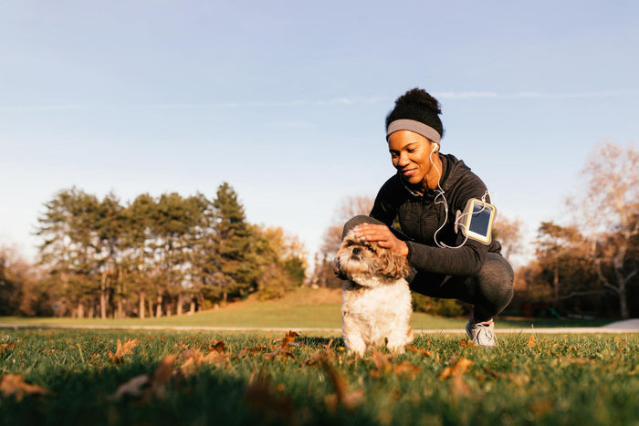 Happy african american sportswoman cuddling her small dog